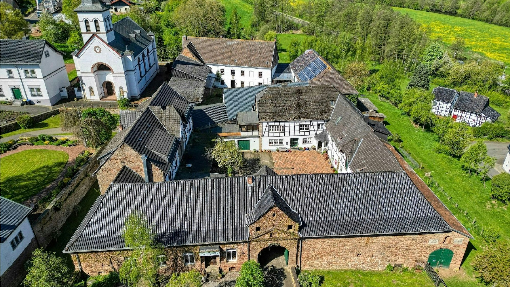 Blick auf das Burggelände und die angrenzende Kirche aus der Vogelperspektive.