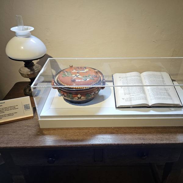 Blick auf eine Vitrine mit einer Wöchnerinnenschüssel und einem aufgeschlagenen Buch.
