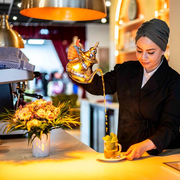 Das Bild zeigt die Betreiberin des Cafés, wie sie einen Pfefferminztee zubereitet.
