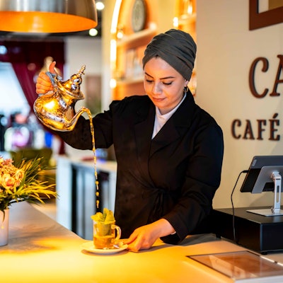 Das Bild zeigt die Betreiberin des Cafés, wie sie einen Pfefferminztee zubereitet.
