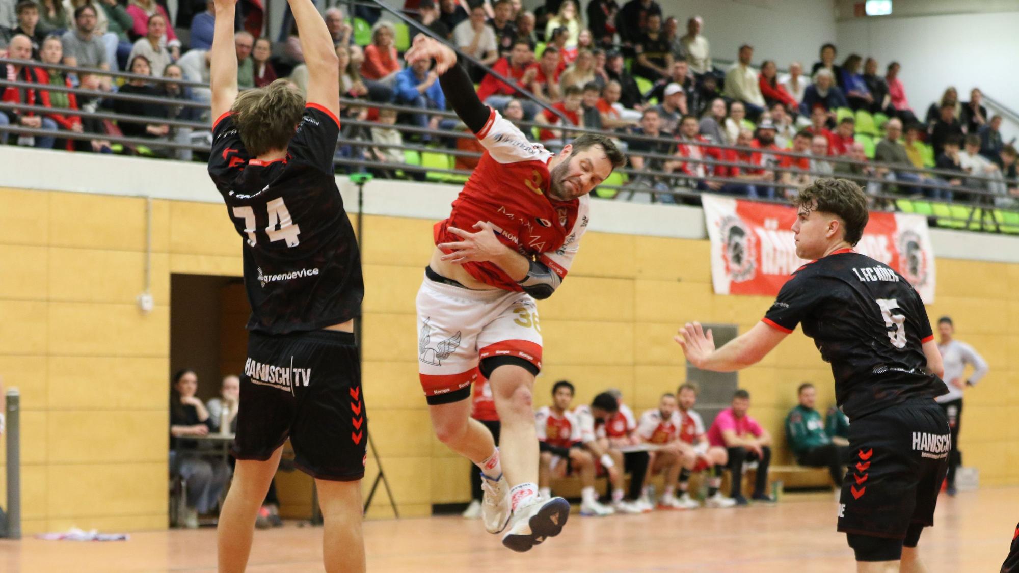 Daniel Schüller wendet seine ganze Kraft auf, um einen Ball zu werfen. Ein Gegenspieler macht sich vor ihm groß.
