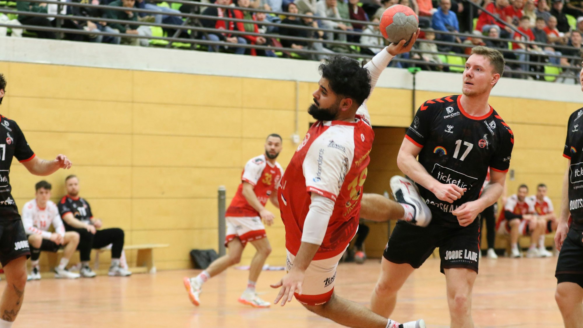 Ali Umat Sinaci liegt beim Wurf quer in der Luft, der Gegenspieler schaut in Richtung eigenes Tor.