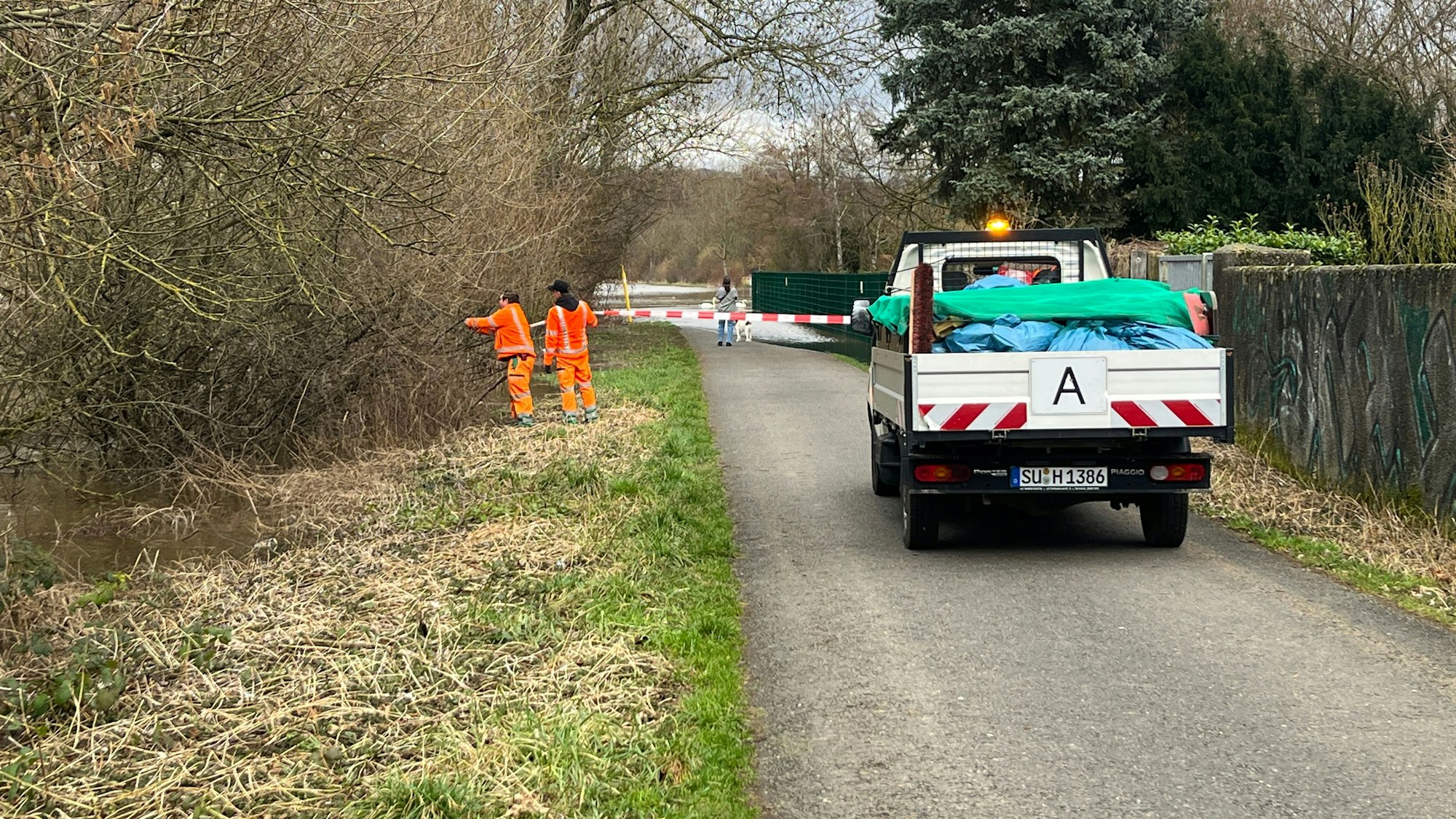 Städtische Mitarbeiter flatterten den Allner Weg ab, der in Teilen unter Wasser stand. Später wurde die Spundwand aufgebaut.
