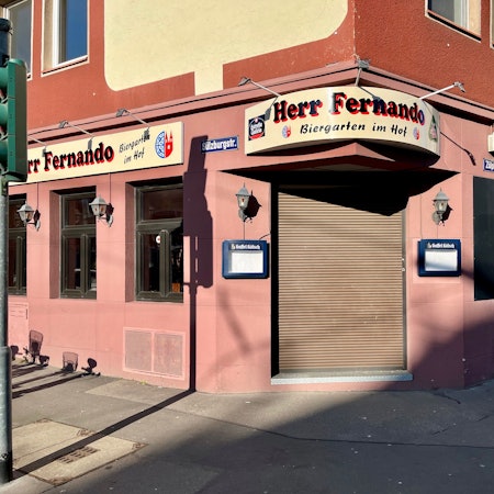 Ein rotgetünchtes Eckhaus ist zu sehen. Das Restaurant darin ist noch geschlossen.