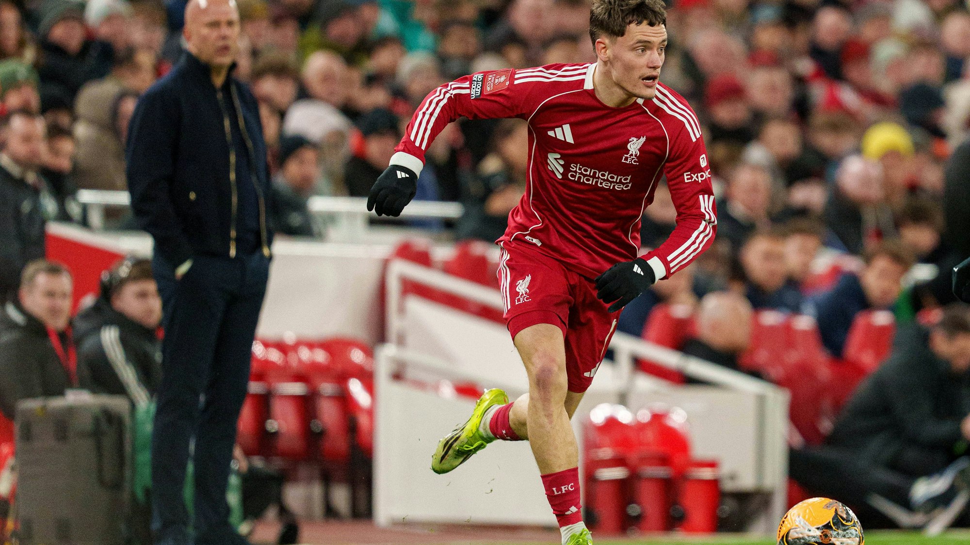 Florian Wirtz läuft, im Hintergrund beobachtet ihn Arne Slot.