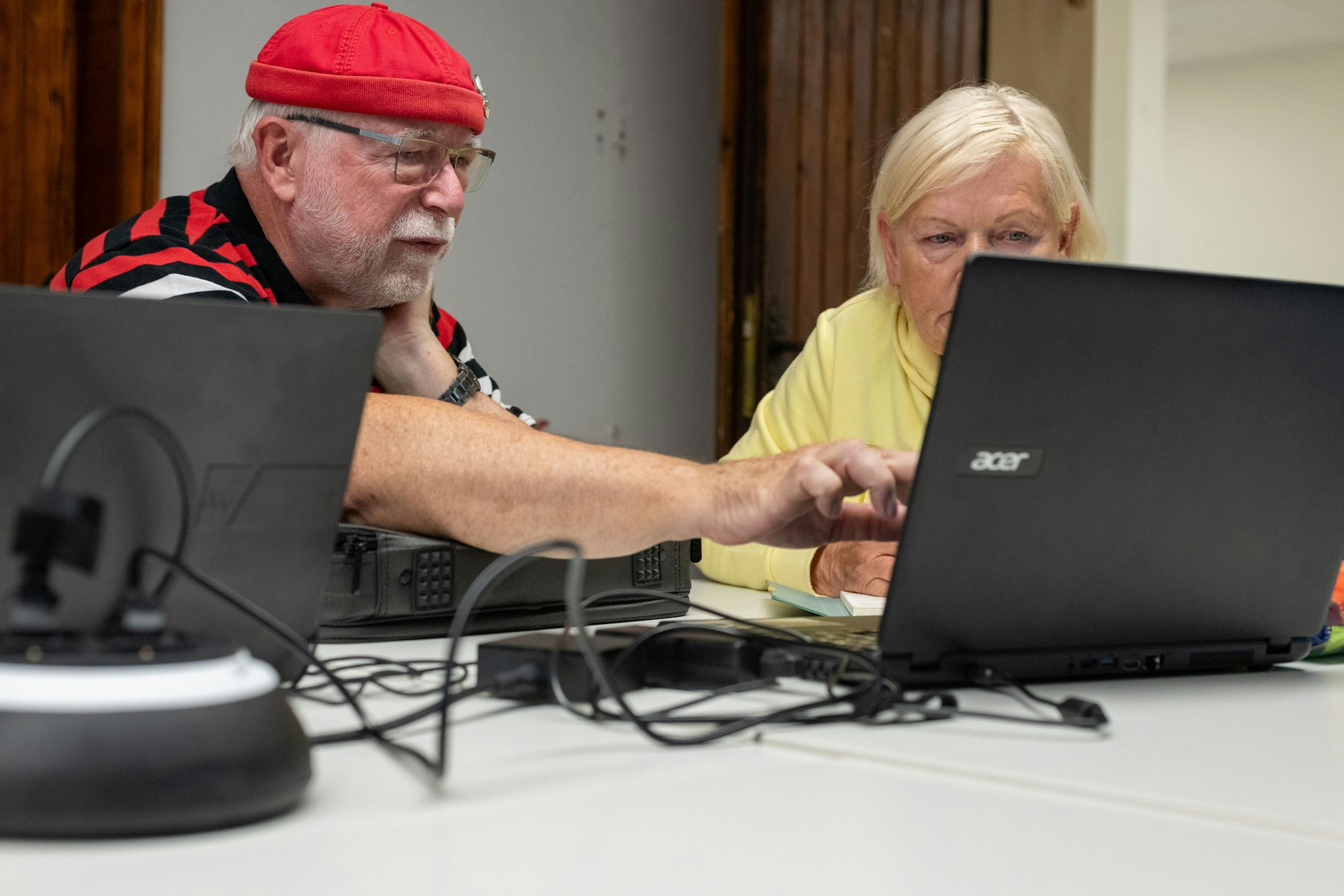Ein Mann und eine Frau sitzen an einem Tisch, vor ihnen stehen Laptops.