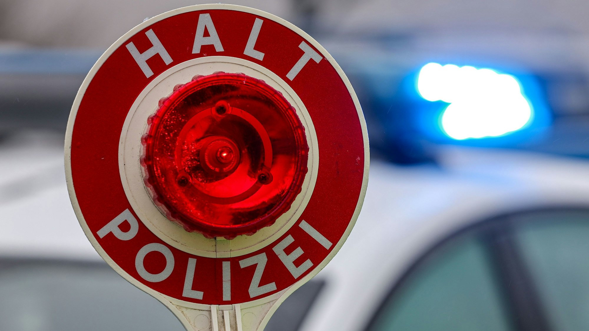 Ein Polizist hält eine Polizeikelle für eine Kontrolle in der Hand.