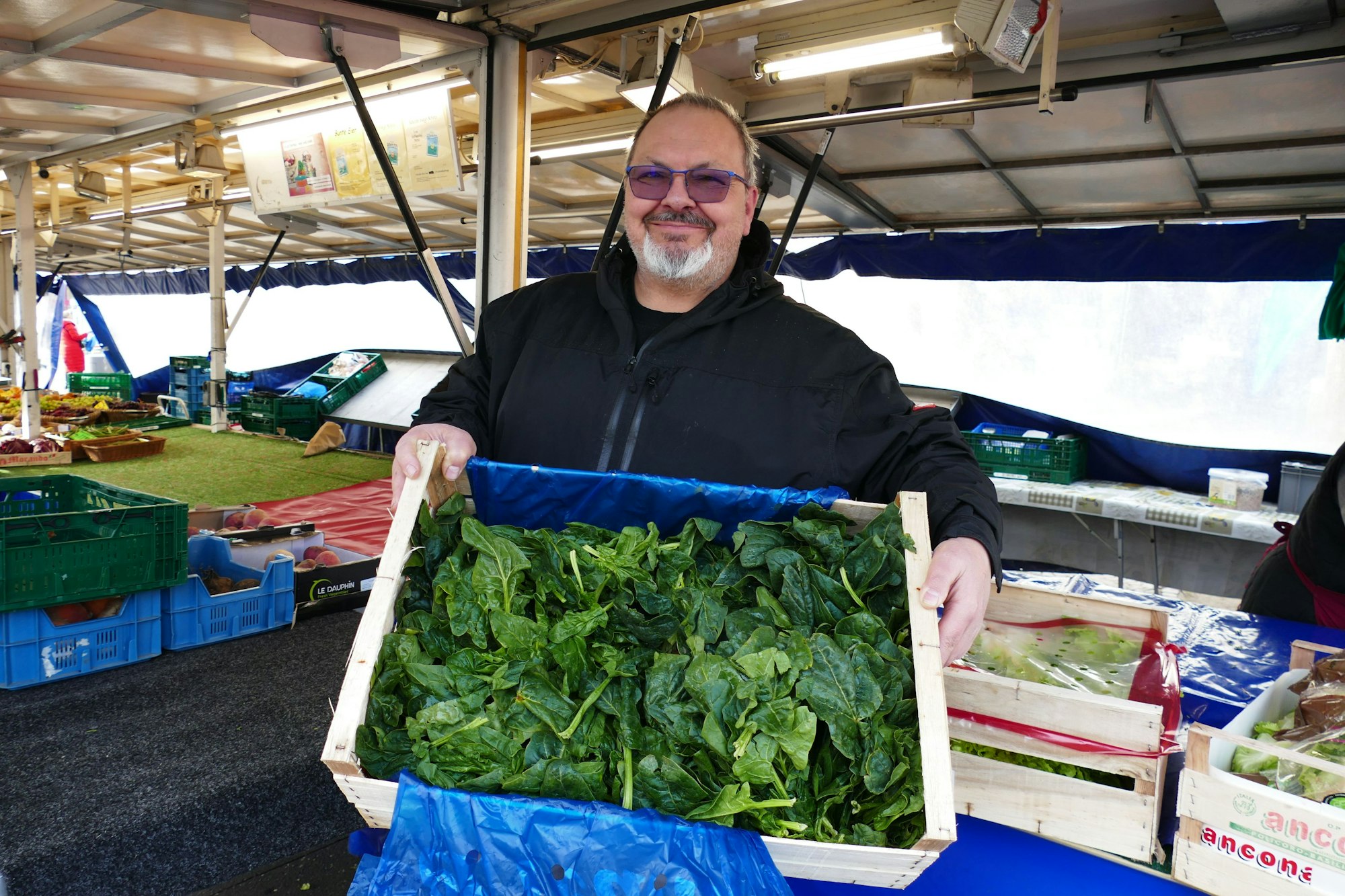 Markthändler Ugur Sezer zeigt eine Kiste mit frischem Spinat, typisch für den Winter.