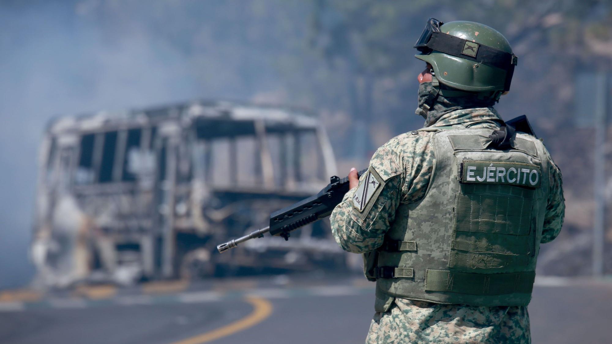 Ein Soldat steht neben einem ausgebrannten Bus, das in Cointzio im mexikanischen Bundesstaat Michoacán, nach dem Tod des Anführers des Kartells der Neuen Generation von Jalisco,