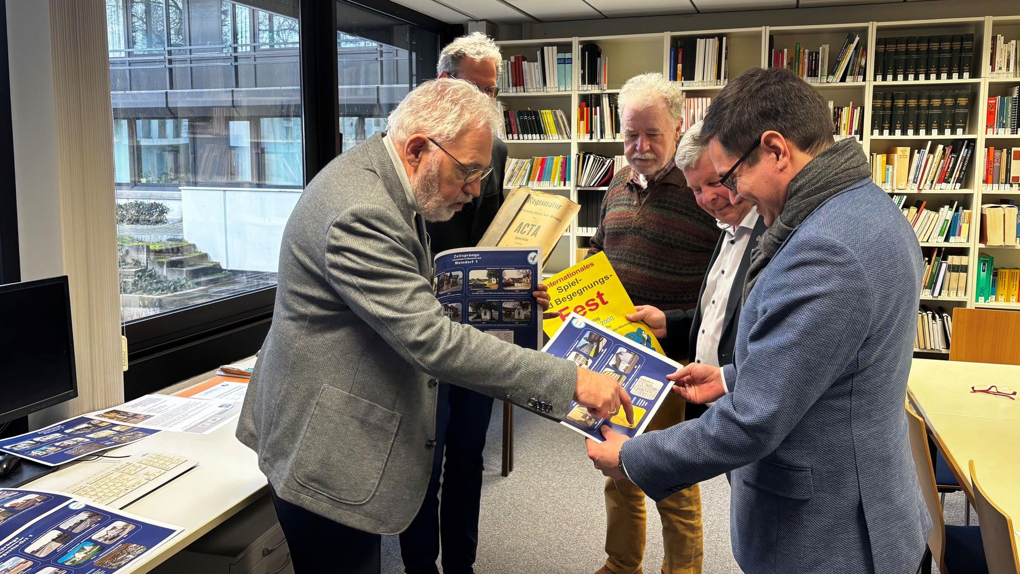 Werner Quadt (Arbeitskreis Stadtgeschichte und Fotogruppe) zeigt Max Leitterstorf (Bürgermeister) einen Teil der Fotoausstellung „Sankt Augustin früher und heute“.