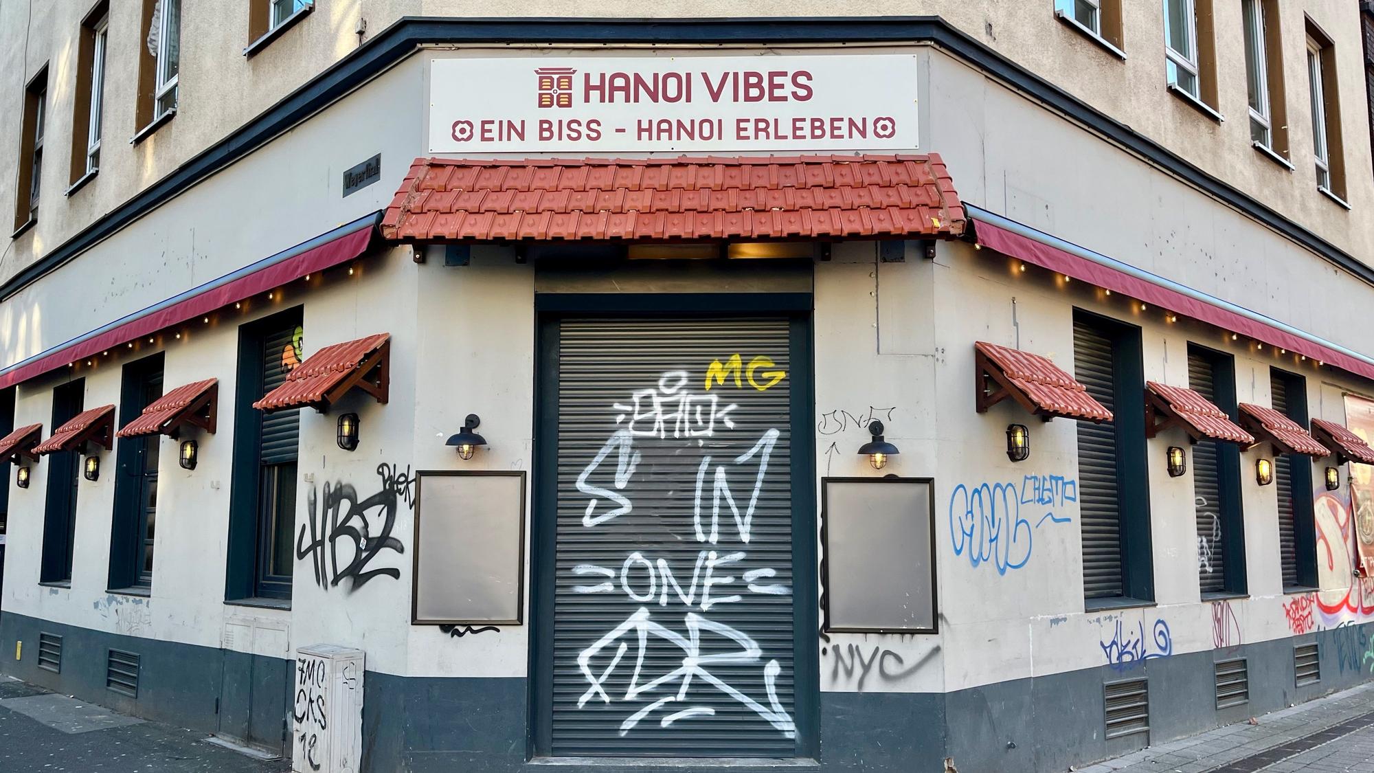 Blick auf ein Ecklokal in einem graffiti-besprühten Haus.