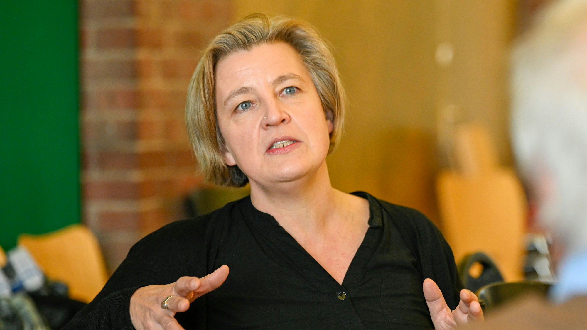 Eine Frau gestikuliert und blickt ernst in die Kamera.