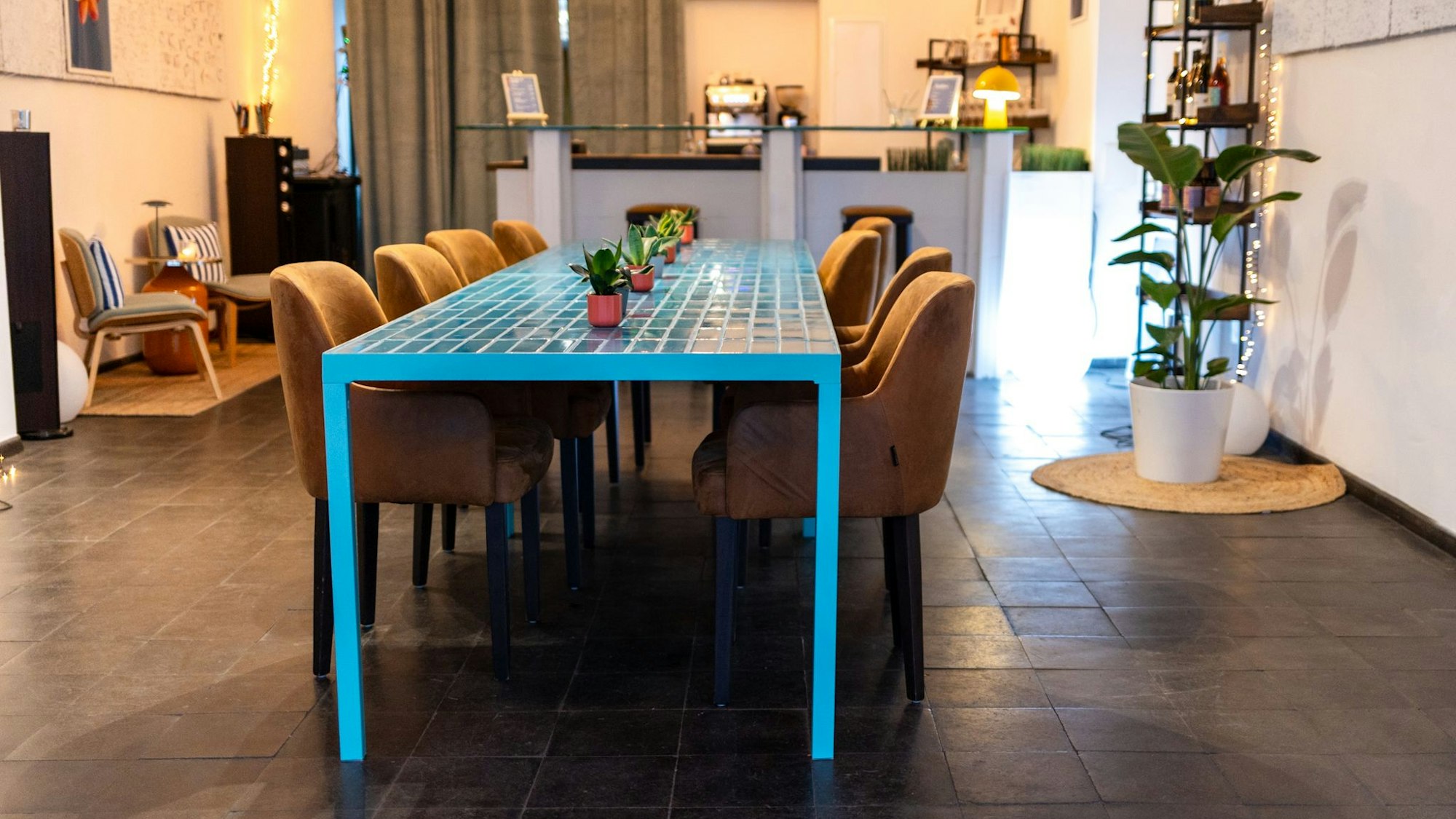 Blick auf blaue Tische mit Fliesen und eine Bar im Hintergrund.