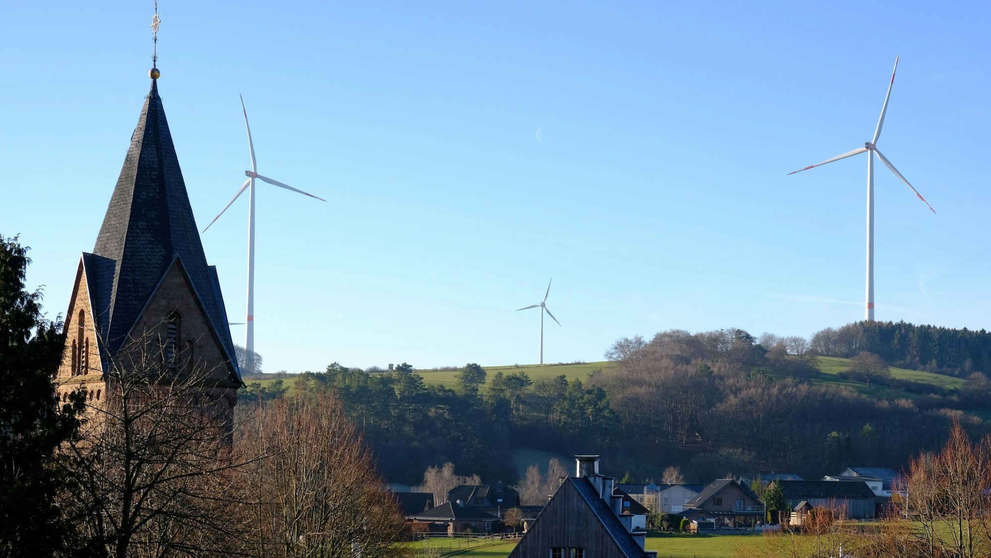 Blick von Kallmuth (im Vordergrund ist der Turm der Pfarrkirche zu sehen) auf den Ravelsberg, wo drei Windkraftanlagen stehen.