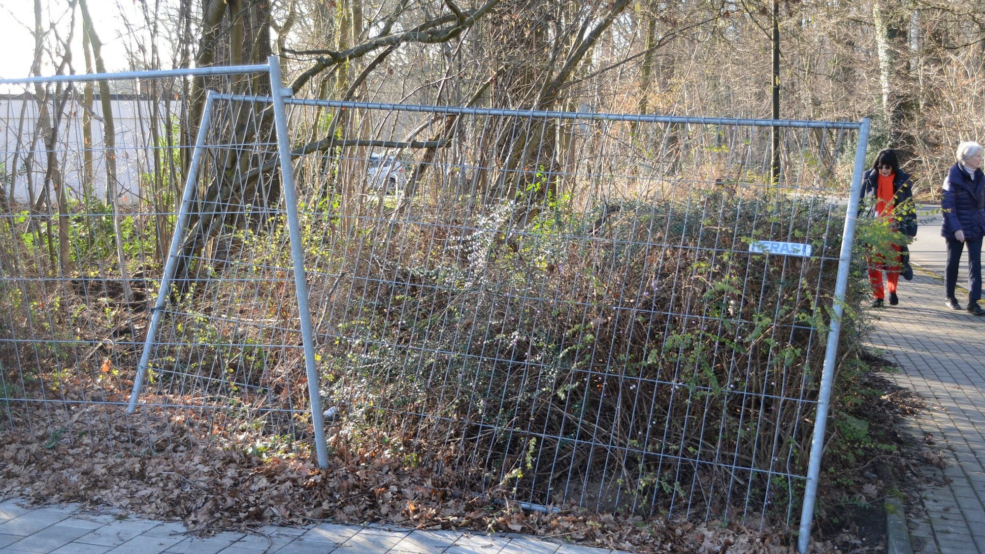 Ein Bauzaun vor Büschen und Bäumen.