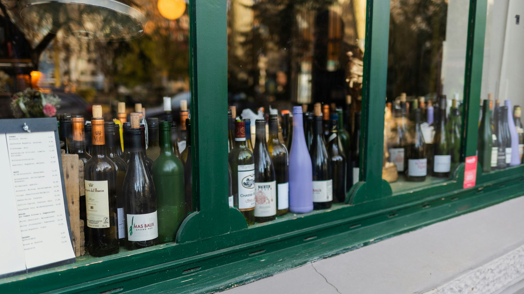 Viele Weinflaschen stehen hinter einer Fensterscheibe.