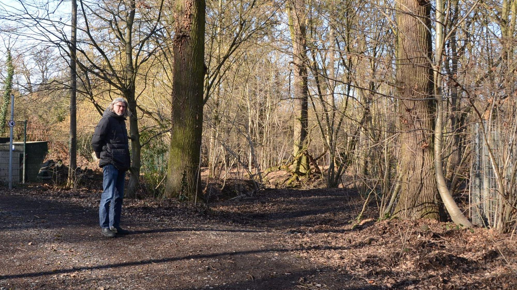 Ein Mann steht an einem Weg im Wald.