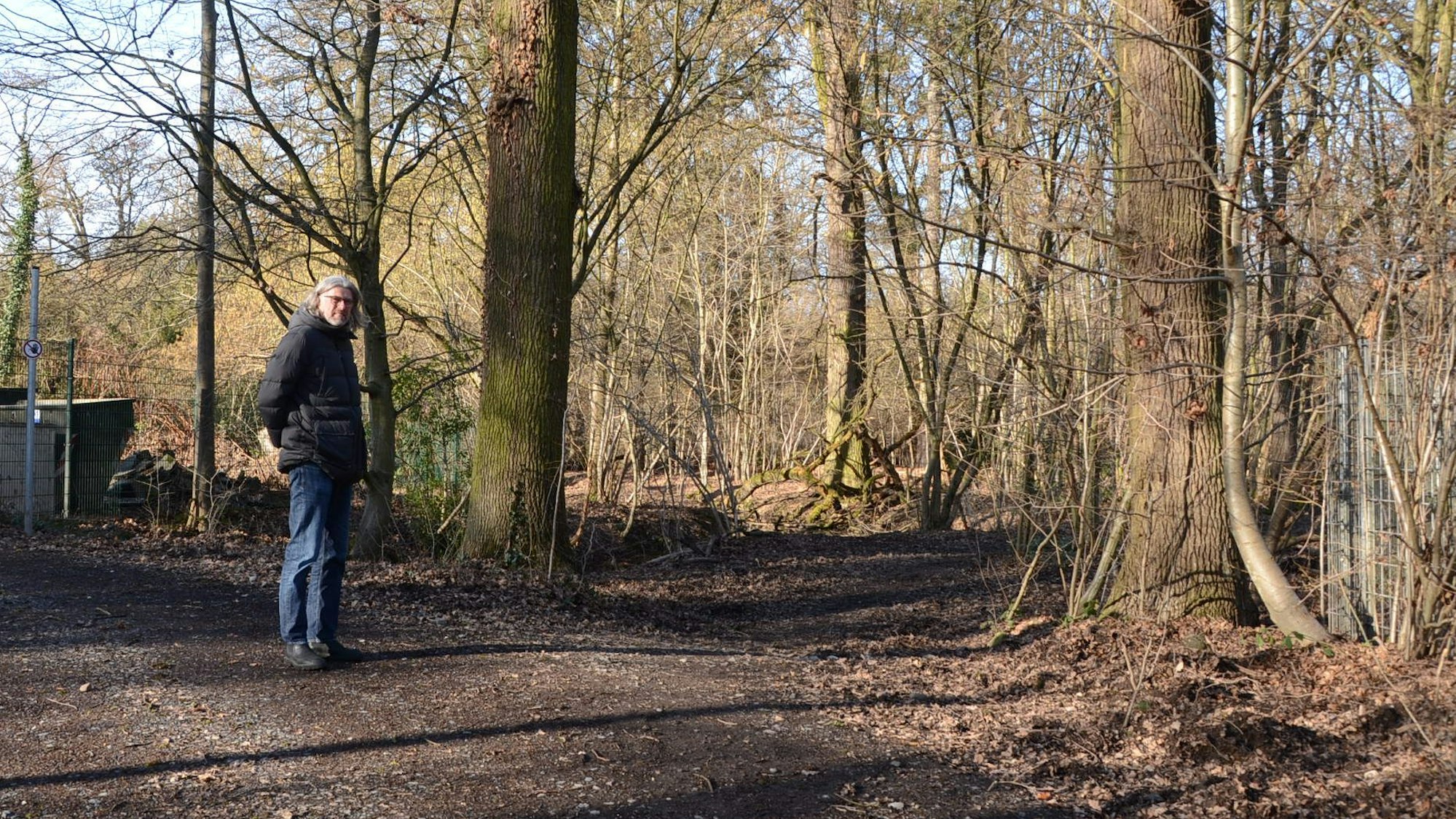 Ein Mann steht an einem Weg im Wald.