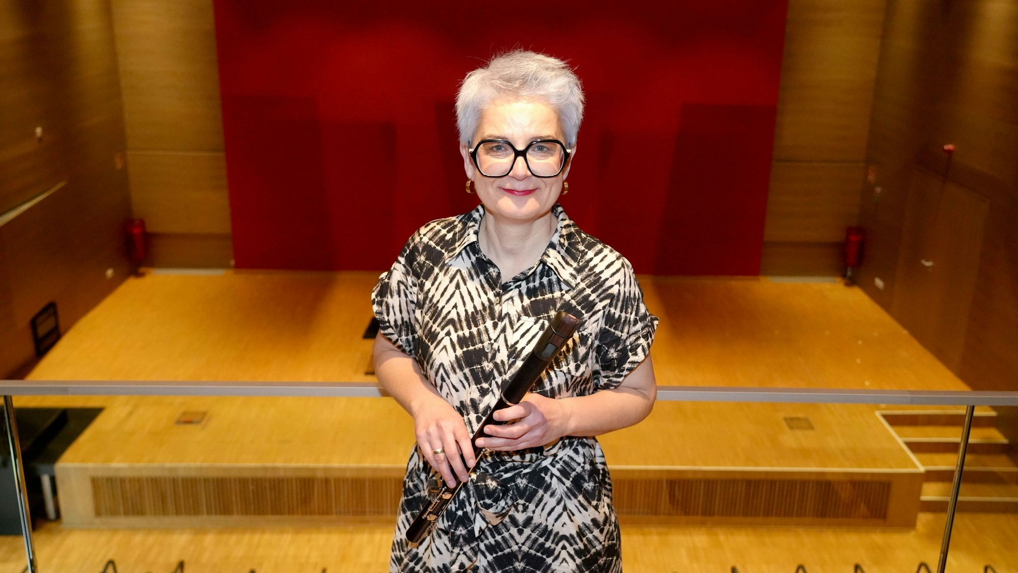 In einem Saal steht eine Frau mit Blockflöte.