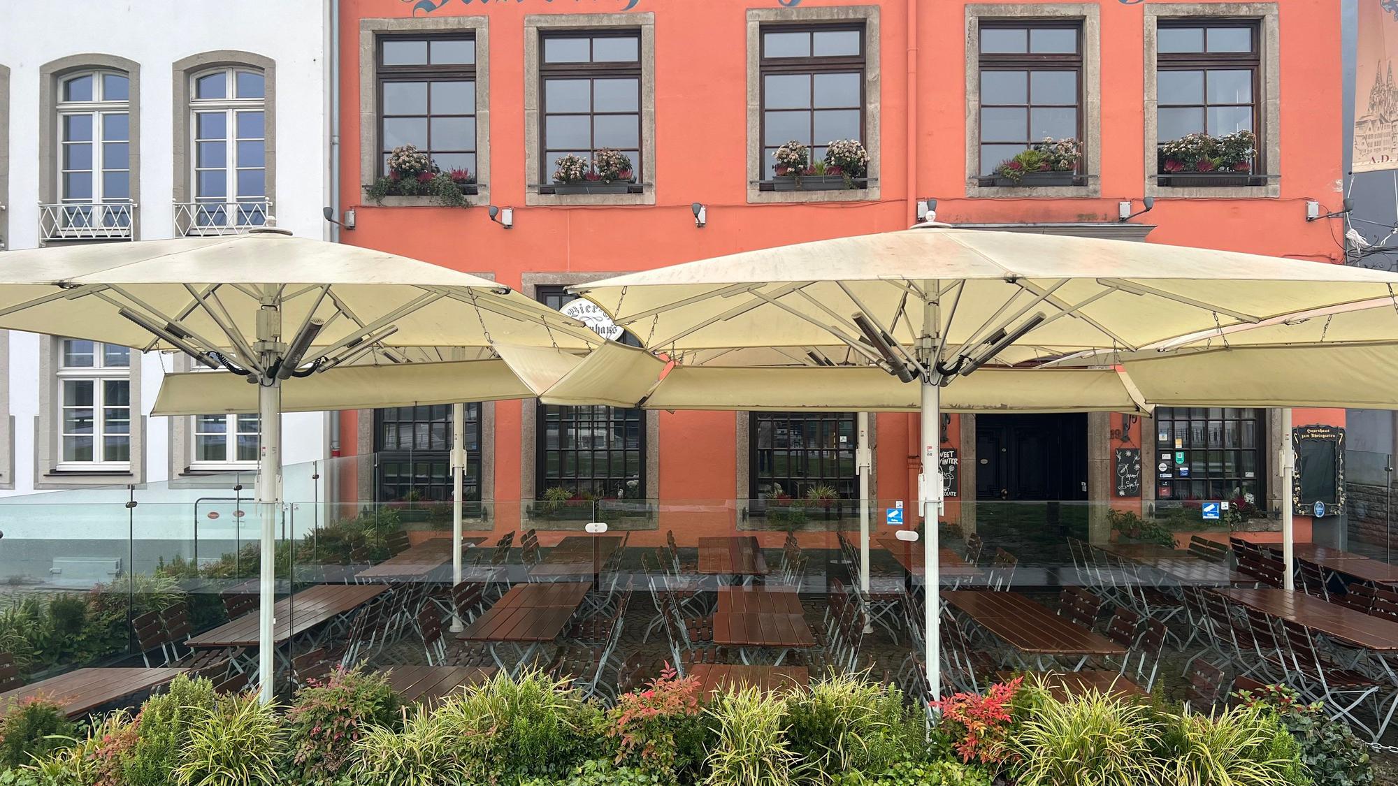 Am Haxenhaus werden transparente Glaselemente verwendet mit Blumenkästen und Sonnenschirmen verwendet.