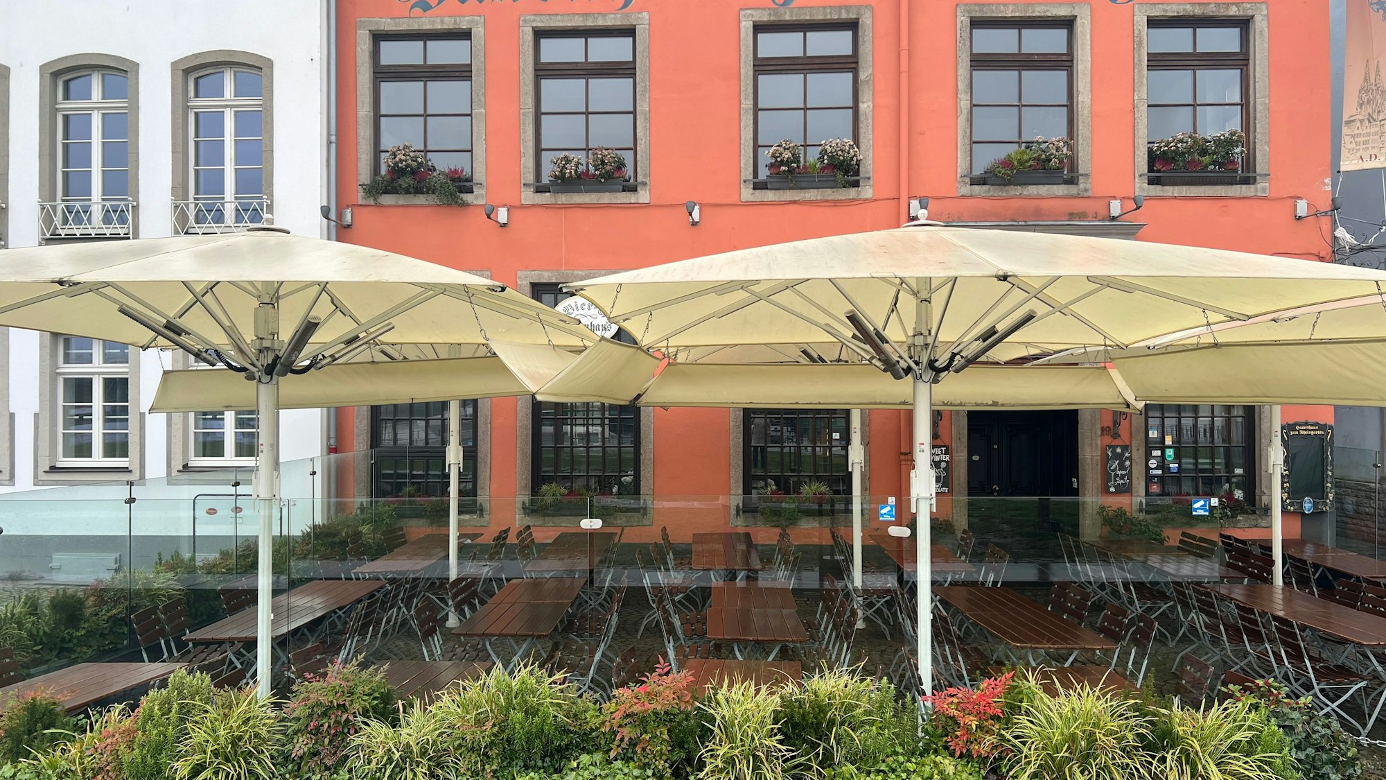 Am Haxenhaus werden transparente Glaselemente verwendet mit Blumenkästen und Sonnenschirmen verwendet.