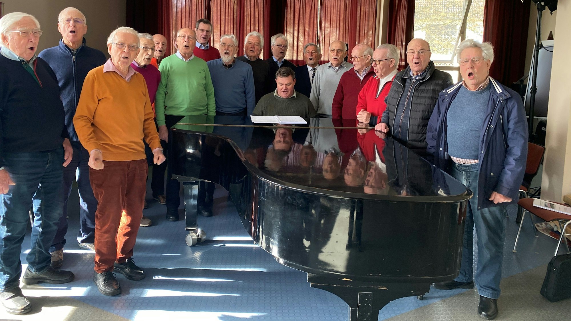 Die Senioren stehen neben einem Flügel und singen.