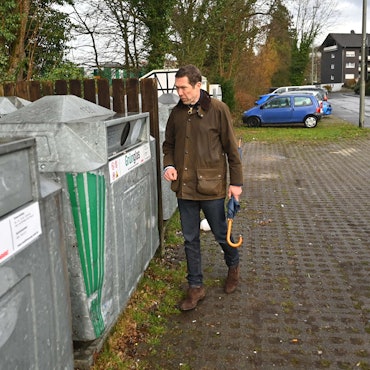 Das Bild zeigt den Gummersbacher Bürgermeister an einem Glascontainer.