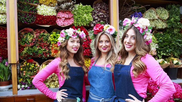 Holländerinnen vom Keukenhof posieren vor einem Blumendisplay.