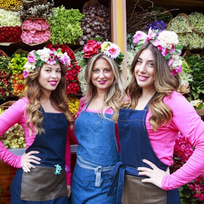Holländerinnen vom Keukenhof posieren vor einem Blumendisplay.