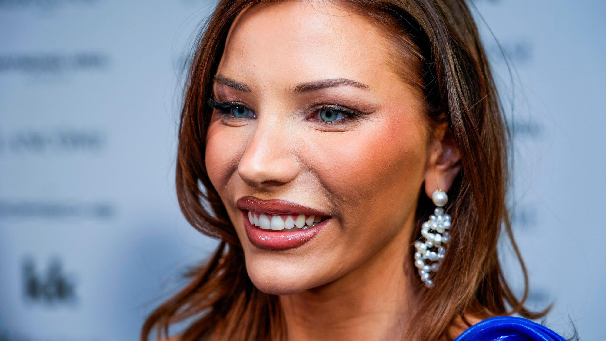 Nora Haukland lächelnd mit Make-up und Schmuck.