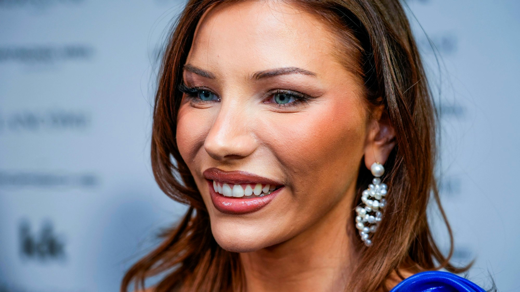 Nora Haukland lächelnd mit Make-up und Schmuck.