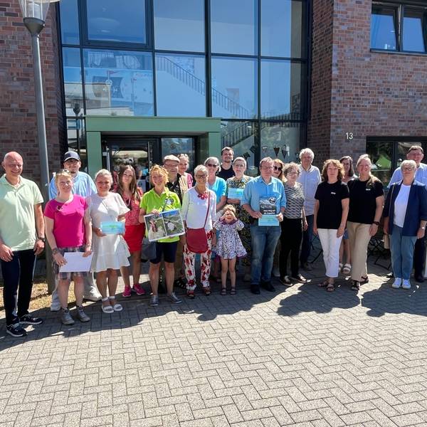 Viele Menschen stehen im Halbkreis vor einem Gebäude.