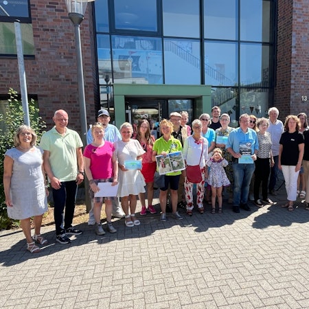 Viele Menschen stehen im Halbkreis vor einem Gebäude.