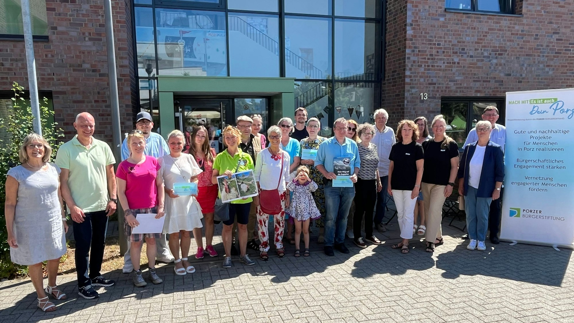 Viele Menschen stehen im Halbkreis vor einem Gebäude.