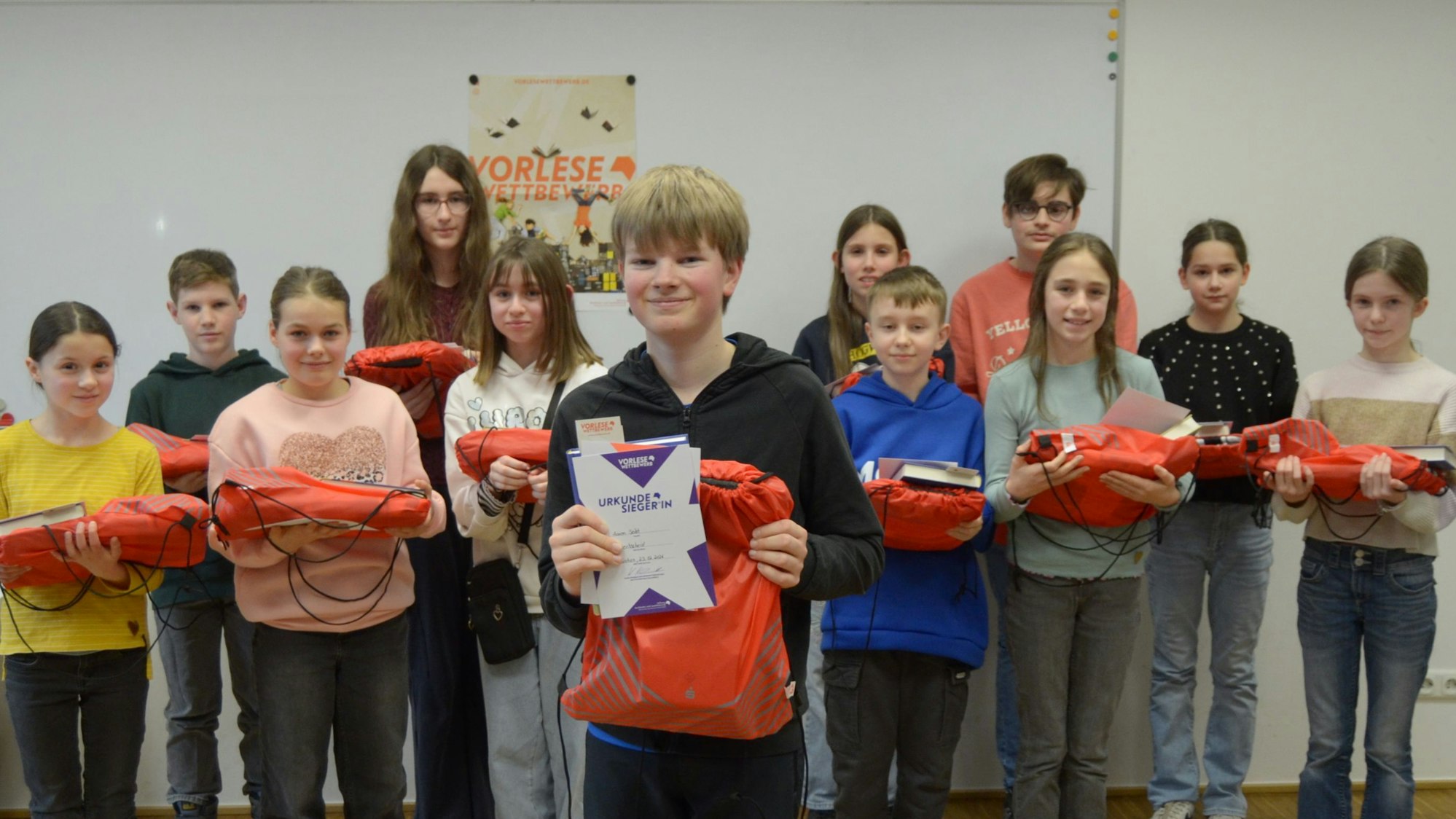 Aaron Seibt lacht in die Kamera, die anderen Teilnehmerinnen und Teilnehmer stehen in zwei Reihen hinter ihm. Alle haben ihre Preise in den Händen.