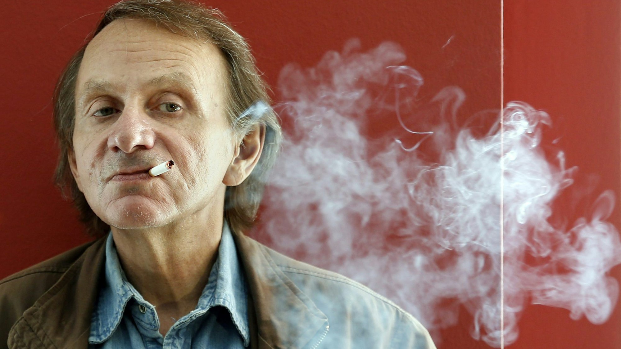 28.04.2015, Spanien, Barcelona: Der französische Autor Michel Houellebecq raucht bei der Präsentation seines Buches «Unterwerfung» eine Zigarette.