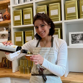 Zu sehen ist Michaela Grigorakis, die Olivenöl in ein Schälchen füllt.