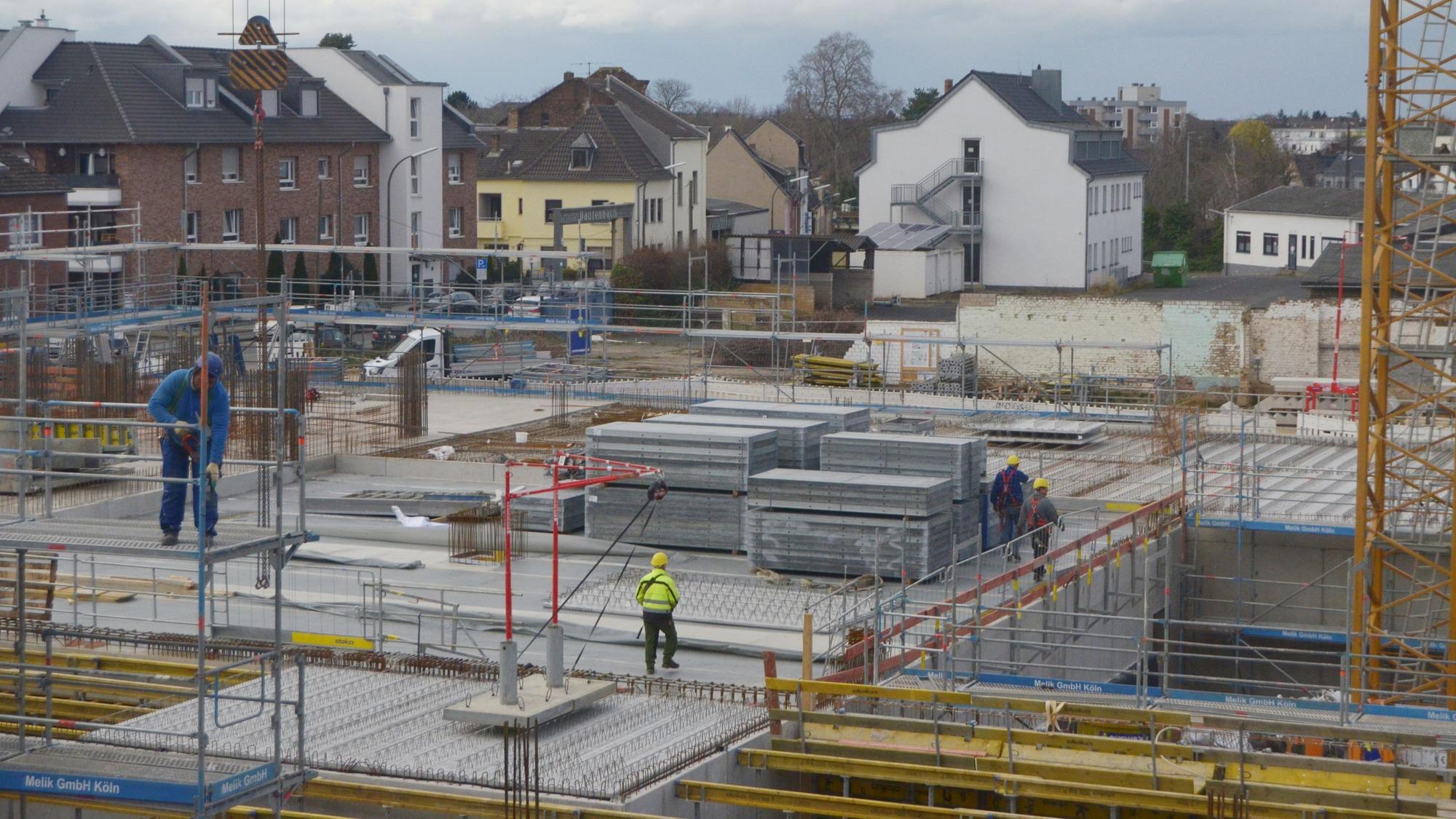 Auf der Baustelle eines großen Gebäudes sind Arbeiter unterwegs.