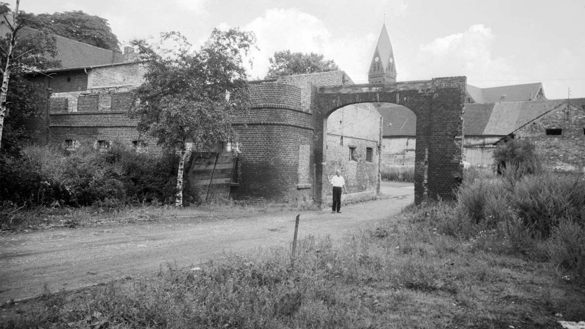Blick auf einen Gutshof, im Hintergrund ist die Rochuskirche zu sehen.