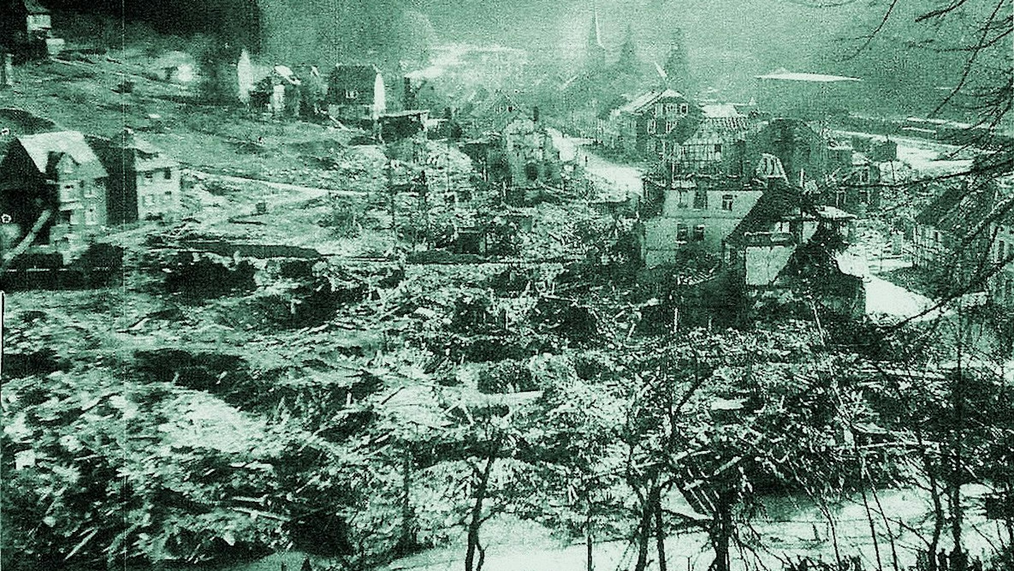 Ein altes Bild von Engelskirchen mit zerbombten und verwüsteten Häusern und Bäumen ist zu sehen. Der Schaden ist enorm.