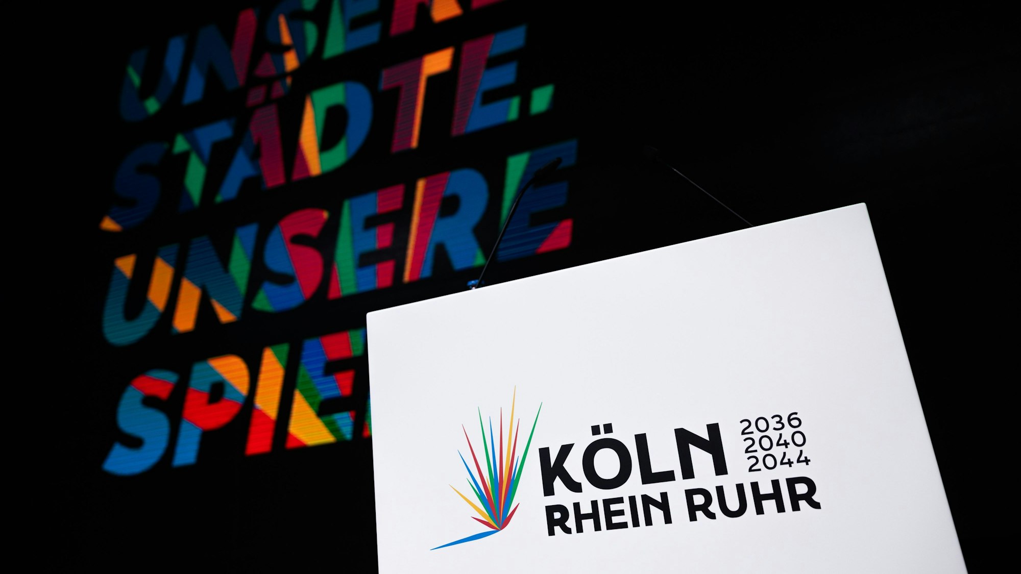 19.01.2026, Nordrhein-Westfalen, Köln: Das Logo ist beim Start der Kampagne für die Bewerbung der Region Rhein-Ruhr, mit Köln als "Leading City", um Olympische und Paralympische Spiele in der Lanxess-Arena zu sehen. Foto: Rolf Vennenbernd/dpa +++ dpa-Bildfunk +++