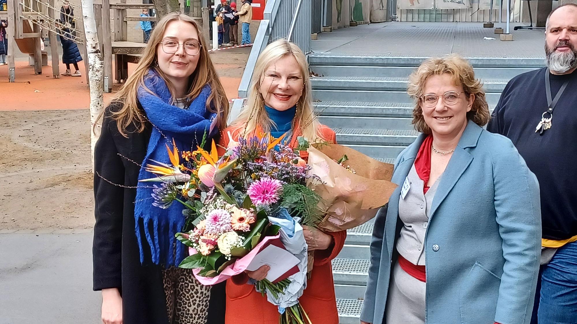 Drei Frauen stehen nebeneinander, die in der Mitte hält mehrere Blumensträuße.