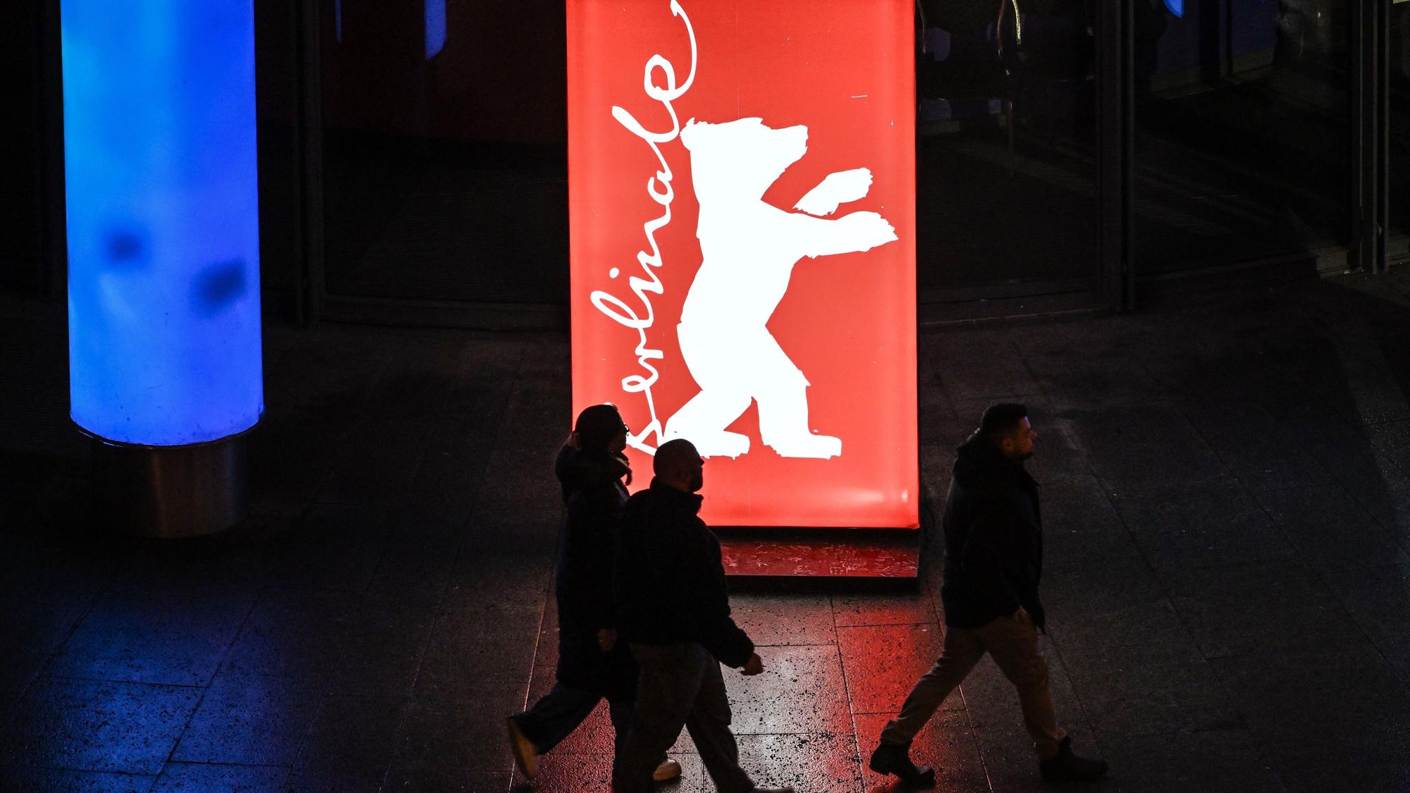 Passanten gehen am Abend der Preisverleihung an einem Berlinale-Plakat vorbei.