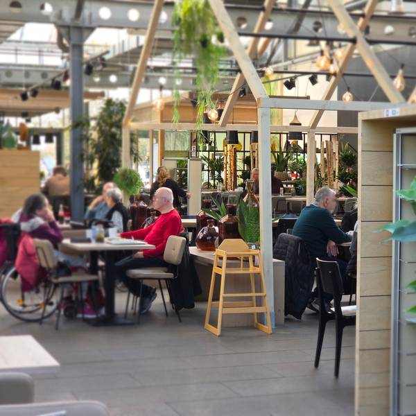 Der Gastraum in der Gartenküche liegt direkt im Gewächshaus und ist passend dekoriert mit viel Grün und Holzoptik.