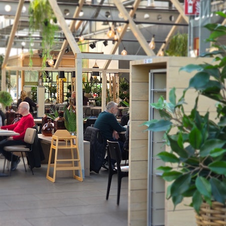 Der Gastraum in der Gartenküche liegt direkt im Gewächshaus und ist passend dekoriert mit viel Grün und Holzoptik.