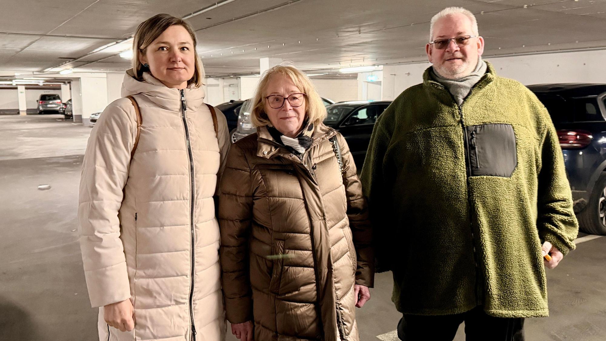 Die beiden Frauen von der Eigentümergemeinschaft und der Hausmeister stehen nebeneinander in der Tiefgarage und blicken in die Kamera.