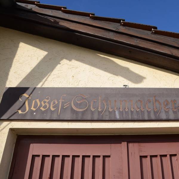 Holzschild über einem Halleneingang. "Josef-Schumacher-Halle" steht darauf.