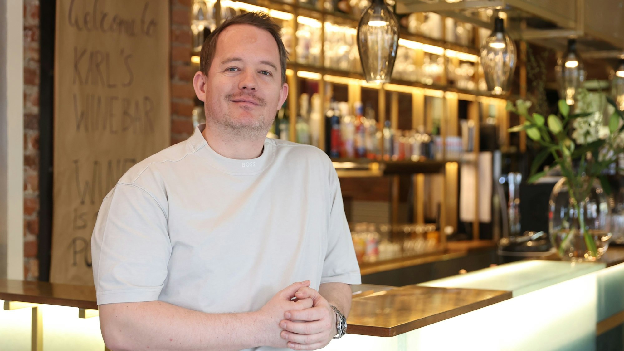 Herr Marx steht an die Bar gelehnt und lächelt in die Kamera.