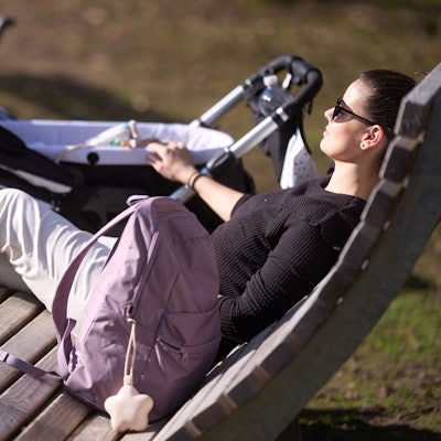 Eine Frau genießt den sonnigen Tag auf einer Bank.