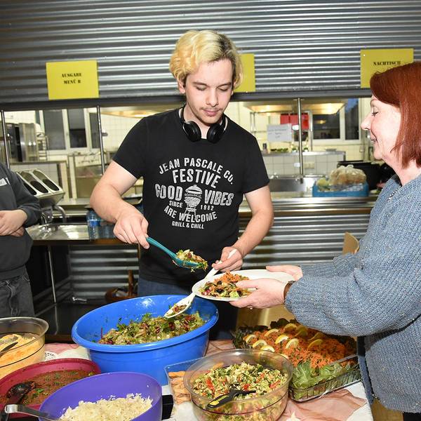 Das Foto zeigt zwei Personen mit einem üppigen Essbuffet.